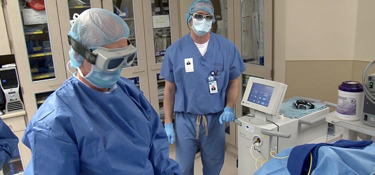 A laser technician stands next to a holmium laser unit as a physician performs a procedure
