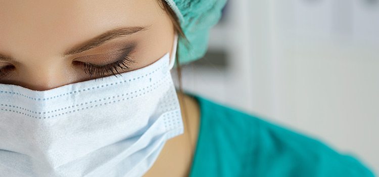 Close up of a nurse wearing a hair net and face mask