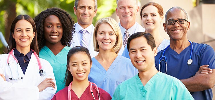 A group of healthcare workers standing together outside and smiling