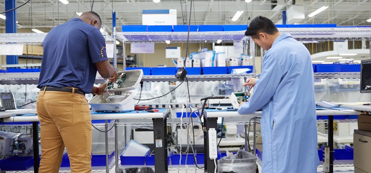 Two biomedical techs repairing broken medical equipment