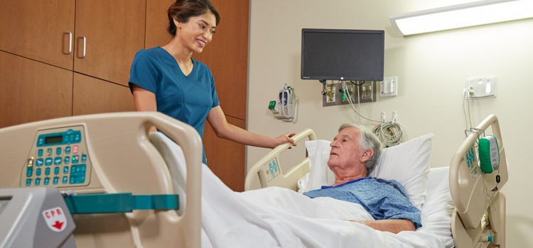 Elderly patient in bed being assisted by a nurse