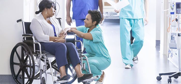 Nurse crouching next to patient in wheel chair