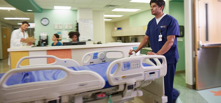 Agiliti team member pushes hospital bed down hallway